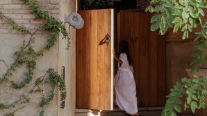 A staircase leading to a wooden door with a keyhole, surrounded by greenery and a brick wall. - Torrearena Design Hotel (Puerto Escondido)
