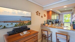 Una cocina con vista al mar, una barra de madera y un área de comedor con dos sillas.