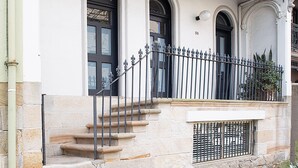 A building with a stone staircase leading to a balcony with a wrought iron railing. - Petite Maison, Potts Point Isyd (Potts Point)