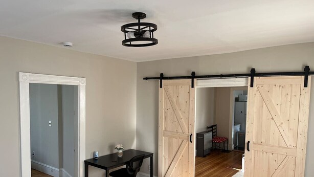 A room with a desk, chair, and a sliding barn-style door. - 5 Min to Salem~Comfy King Beds (Beverly)