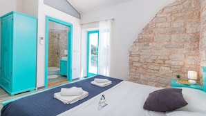 Ein Schlafzimmer mit Bett, ein Badezimmer mit Dusche und eine Steinwand.