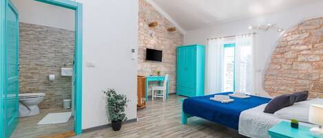 A modern bedroom with a bed, a desk, and a bathroom.