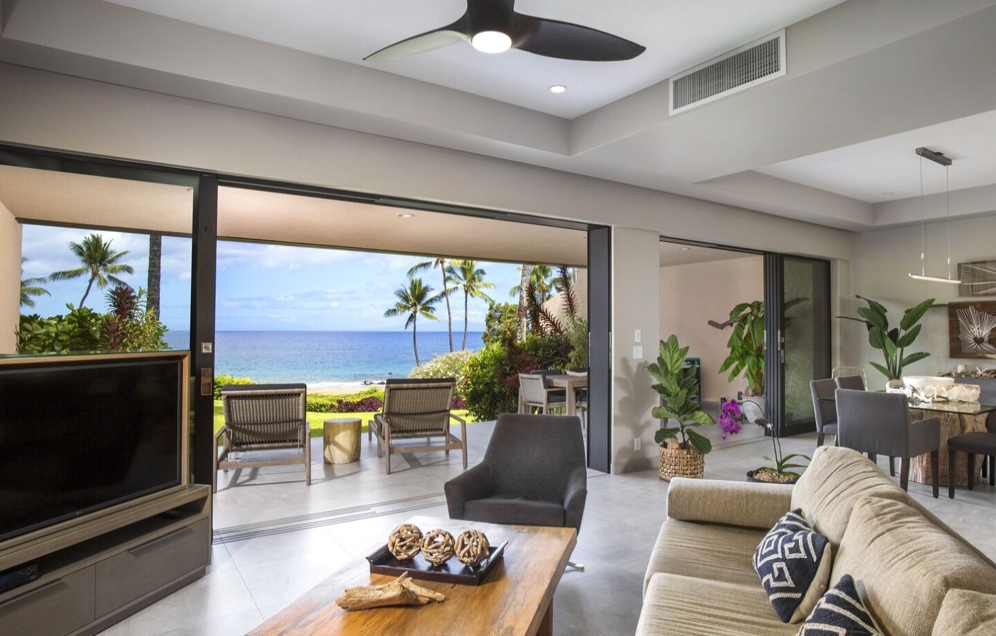 A spacious living area with a large TV, comfortable seating, and a view of the ocean.