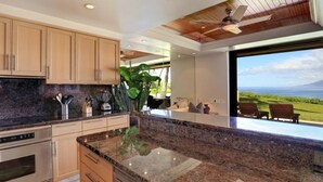 Una cocina moderna con encimeras de granito, electrodomésticos de acero inoxidable y armarios de madera.