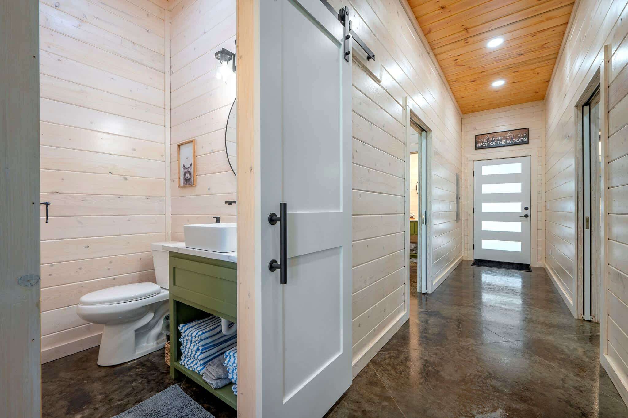 Interior de madera con una puerta blanca, un inodoro y un lavabo.