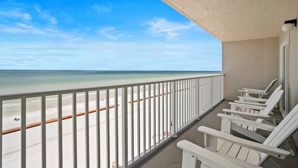 Ein Balkon mit weißen Geländern, der auf einen Strand blickt.
