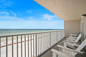 Ein Balkon mit weißen Geländern, der auf einen Strand blickt.