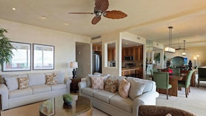 A spacious living room with a sofa, a coffee table, and a ceiling fan. - 2nd Floor Ocean Views | Epic Sunsets | Makena Surf F208 (Wailea)