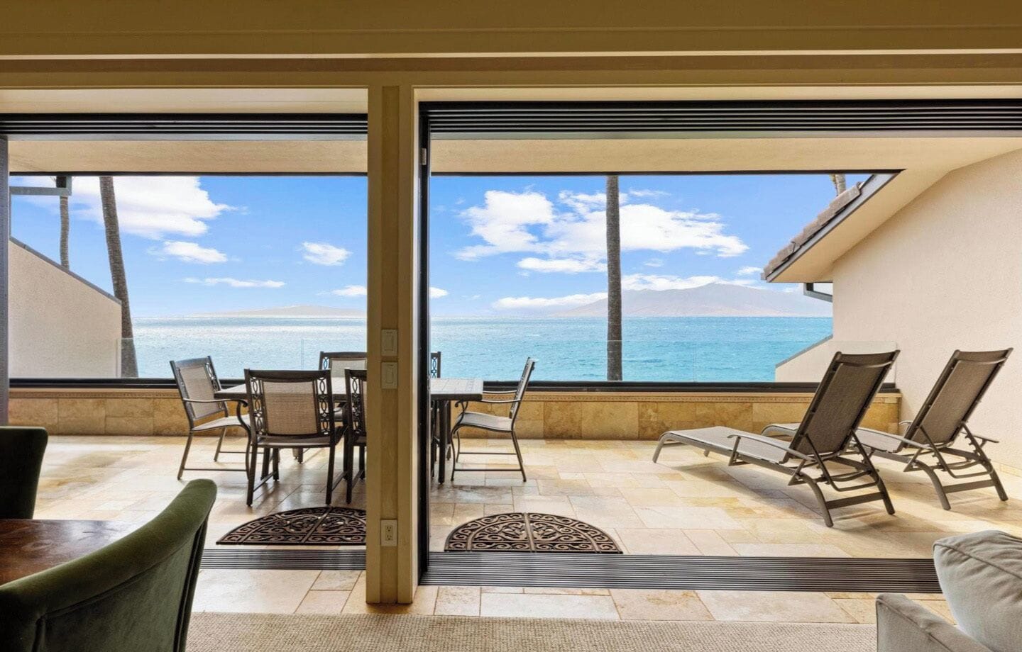 A balcony with a view of the ocean, furnished with chairs and a table.