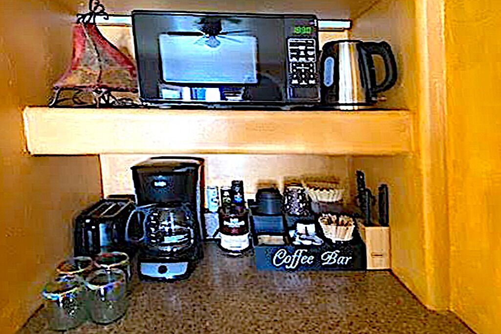 Une cuisine équipée d’un four à micro-ondes, d’un grille-pain, d’une machine à café et d’un espace dédié à la préparation du café.
