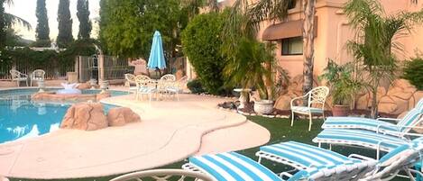 Un espace piscine agrémenté de chaises longues, d’une petite cascade et d’une végétation luxuriante.