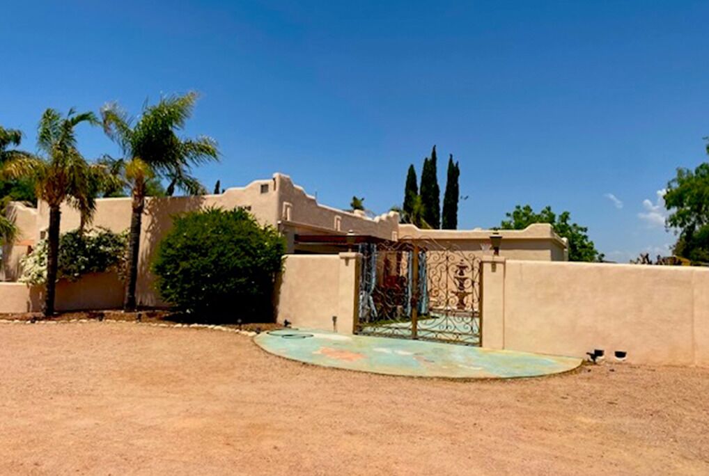 A desert landscape with a building featuring a metal gate and a small courtyard.