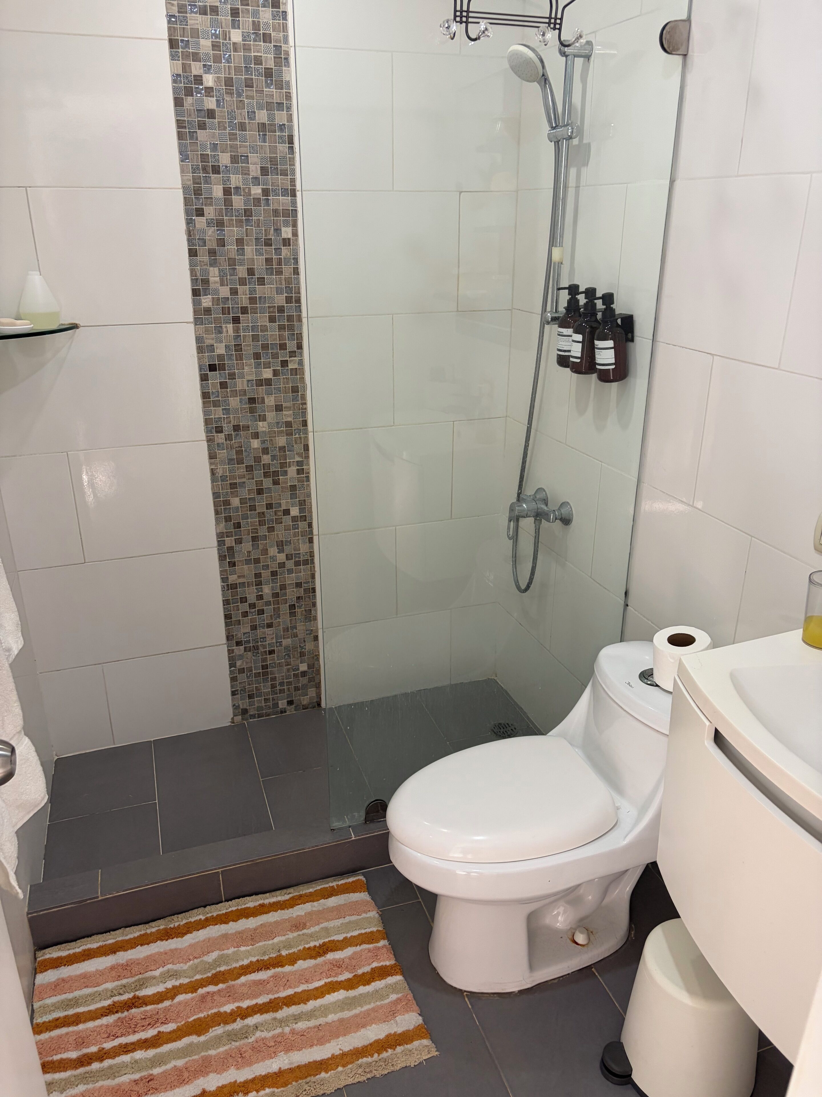 A bathroom with a shower, toilet, and a tiled floor.