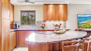 Una cocina moderna con armarios de madera, encimera de mármol y una isla grande con sillas.