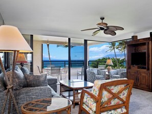Un salón moderno con un amplio ventanal que da a un balcón con vistas al océano.