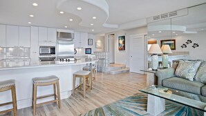 A modern kitchen with white cabinets, stainless steel appliances, and a central island with stools.