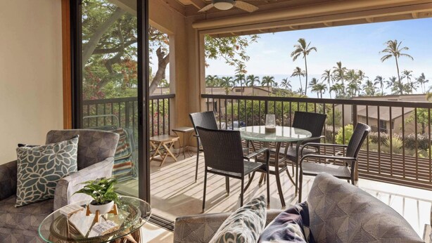 Un balcon avec une table en verre, des chaises et un canapé.