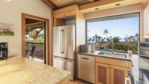 Une cuisine moderne dotée de plans de travail en granit, d’appareils électroménagers en acier inoxydable et de meubles en bois.