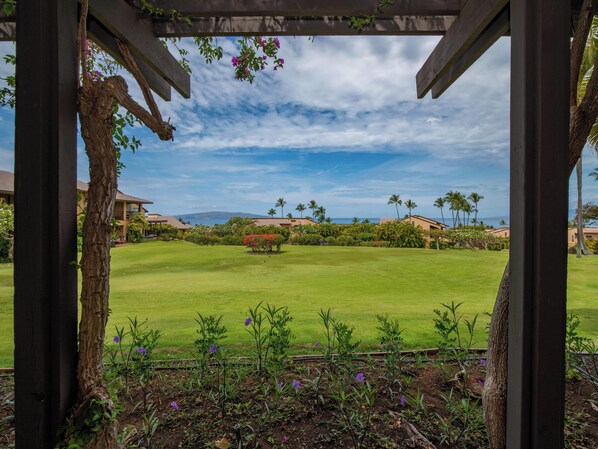 A golf course with a wooden pergola structure, lush green grass, and a clear sky.
