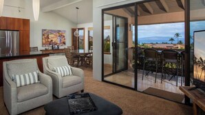 A modern living room with a large sliding glass door leading to a balcony with a view of the ocean.