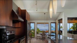A modern kitchen with wooden cabinets, a large island, and a view of the ocean.