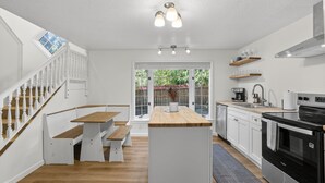 A modern kitchen with white cabinetry, a wooden island, a built-in oven, and a staircase with white railings. - Garden Home Estate, Two Kitchens (Portland)