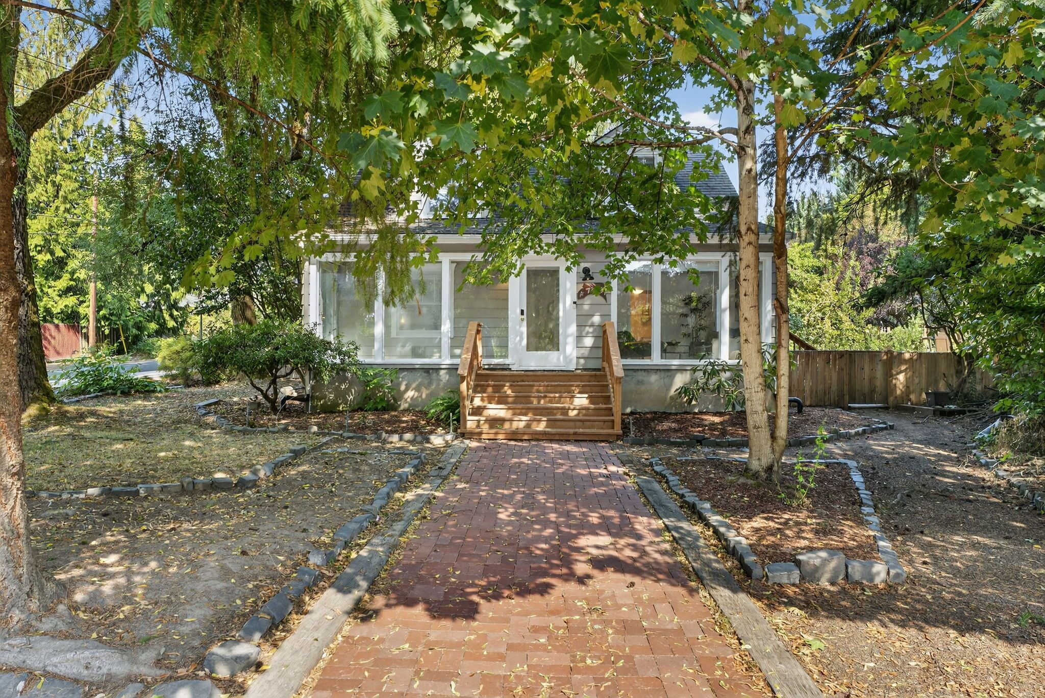 A brick pathway leading to a house with a wooden porch.