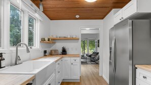 A modern kitchen with white cabinets, a stainless steel refrigerator, and wooden countertops. - Garden Home Estate, Two Kitchens (Portland)