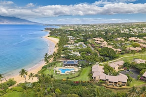 A coastal resort with a swimming pool, beachfront, and lush greenery.