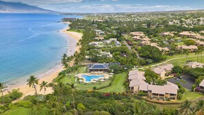 A coastal resort with a swimming pool, beachfront, and lush greenery.