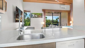 A modern kitchen with a large island, stainless steel sink, and a ceiling fan. - Stylish Beach Studio - Professional Managed (Wailea)