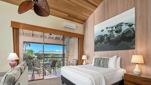A hotel room with a large bed, a balcony with a view of palm trees, and a painting of rocks on the wall. - Stylish Beach Studio - Professional Managed (Wailea)