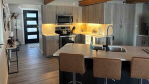 Une cuisine moderne avec des meubles en bois, des appareils en acier inoxydable et un îlot central doté de tabourets de bar.