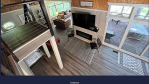 Un intérieur doté d’un plafond en bois, d’une cheminée, d’un téléviseur et d’un coin repas.