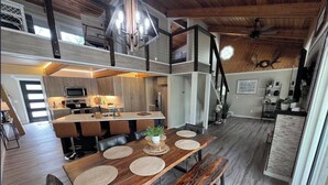 Un espace repas avec une table en bois, des bancs et un lustre.