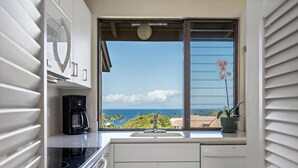 A kitchen with a view of the ocean, a coffee maker, and a potted plant. - Wailea Ekahi Village 54D | Sweeping Ocean Views, Updated Kitchen & Resort Pools (Wailea)