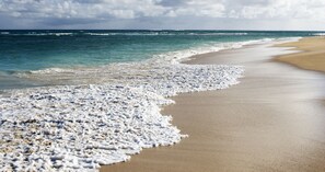 A beach with a wide sandy shore and gentle waves.