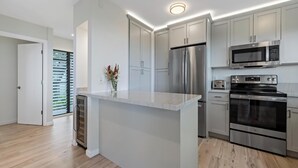 Une cuisine moderne dotée d’appareils électroménagers en acier inoxydable, d’un plan de travail en marbre et de meubles de couleur claire.