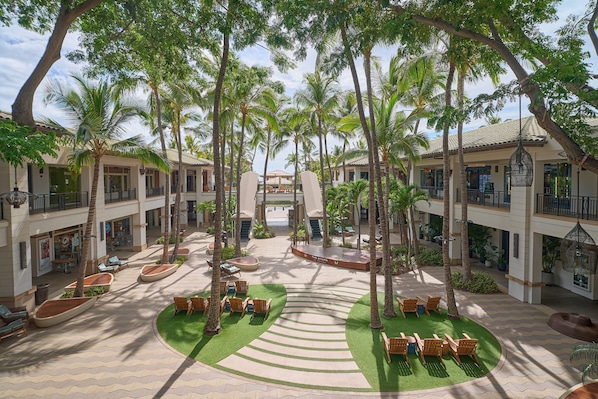 A courtyard with palm trees, outdoor seating, and a central open space.