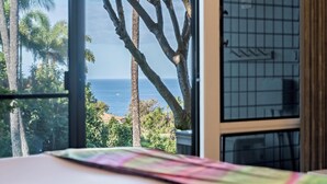 A room with a large window overlooking a coastal view, including palm trees and the sea. - Spacious Wailea Condo - Professionally Managed - Ekolu 1607 (Wailea)