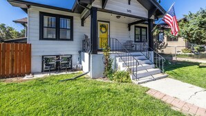 Ein eingeschossiges Haus mit Veranda, einer kleinen Sitzgelegenheit im Freien und einer Flagge.