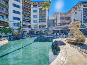 A resort pool area with clear water, lounge chairs, and a decorative wicker chair. - Oceanfront with Private Plunge Pool (Wailea)