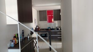 Una cocina moderna con armarios oscuros, un ventanal rojo y un horno empotrado.