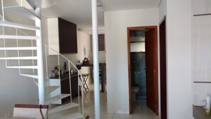 Un interior moderno con una escalera, una zona de cocina y un baño visible a través de una puerta abierta.