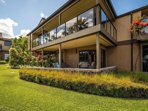 Une maison moderne à deux étages, dotée d’un patio couvert, d’un aménagement paysager luxuriant et offrant une vue sur un ciel dégagé.