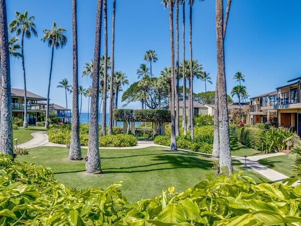 A resort with multiple-story buildings, palm trees, and a well-maintained lawn. - Wailea Elua Village 1303 - 2 Bedroom Oceanfront Condo (Wailea)