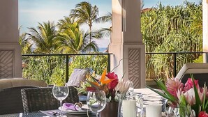 A table set for dining with a view of palm trees and a fence.