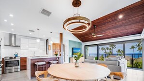A modern kitchen with built-in appliances, a dining area with a wooden table and chairs, and a large window overlooking a scenic view.