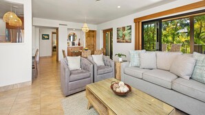 Ein modernes Wohnzimmer mit einer Couch, zwei Sesseln, einem Couchtisch und einem Deckenventilator.
