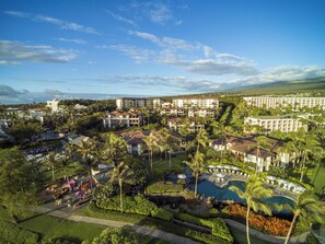 A resort with multiple buildings, a swimming pool, and lush greenery.
